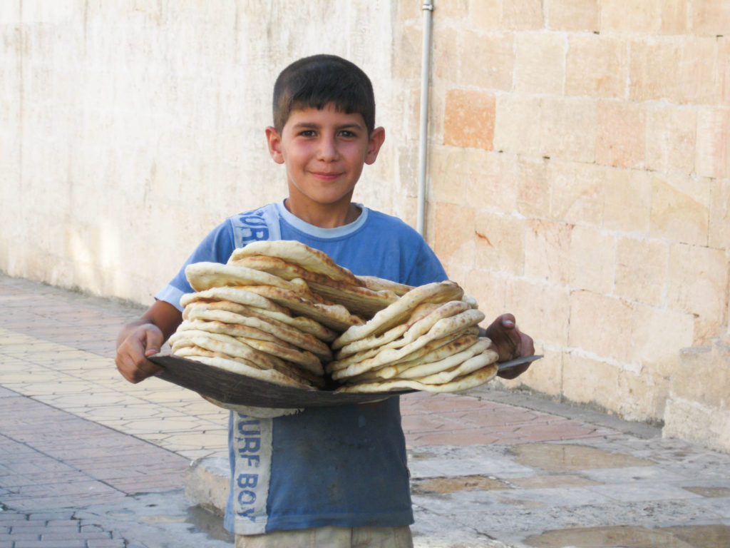 A little boy delivers hot bread to his neighbors. Turkish bread is an iconic and tasty treat.