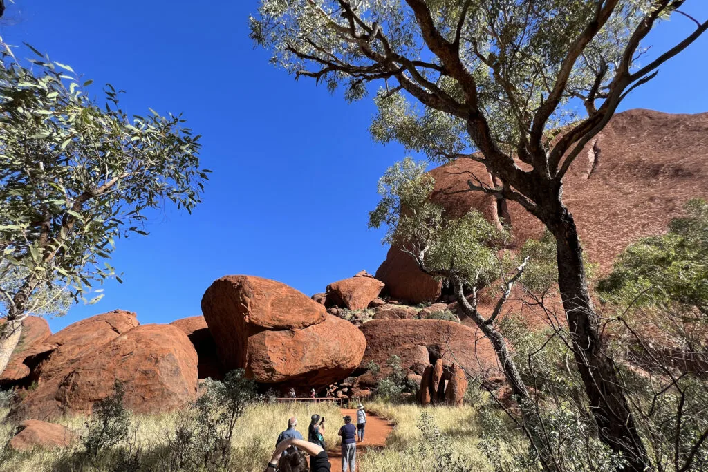 Uluru visitors walk up a trail to an Aboriginal rock art site Australia’s Uluru-Kata Tjuta National Park.
