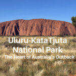 Uluru, a massive red rock formation on a grassy plain in Australia’s Outback.