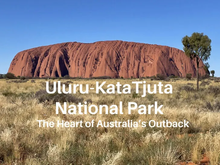 Uluru, a massive red rock formation on a grassy plain in Australia’s Outback.