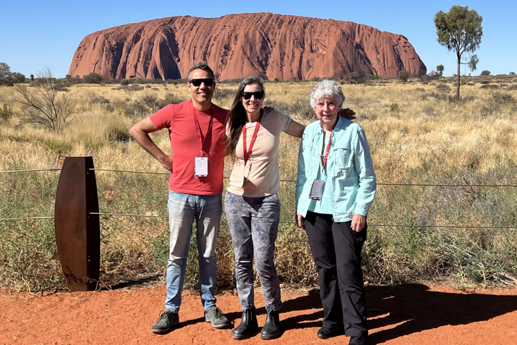 Visitors taking a family photo with Uluru in the background.