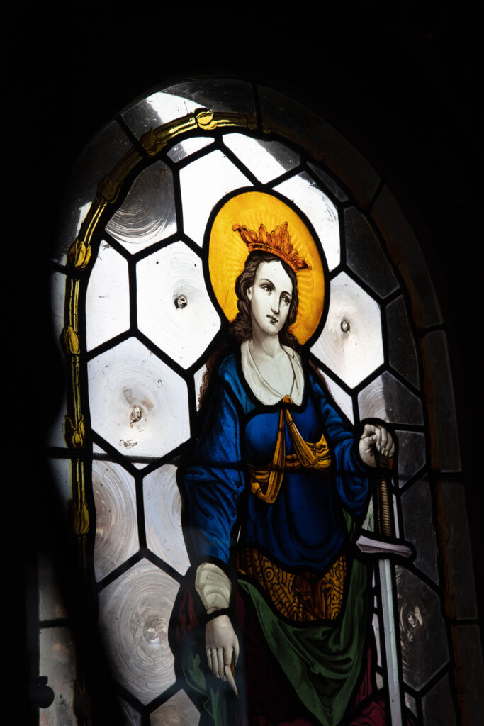 A stained glass window depicting a female saint holding a sword.