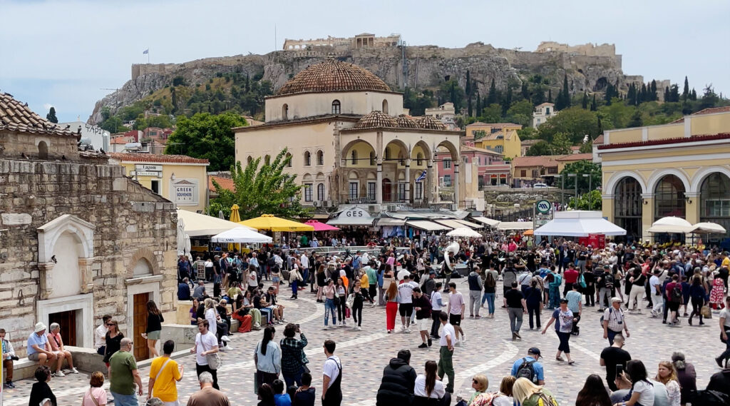 Lively Monastiraki Square filled with people, shops, and a Metro Station.