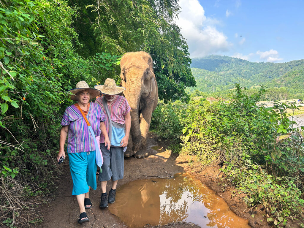 Corinne and Jim walking with Bua Bann through a jungle path.